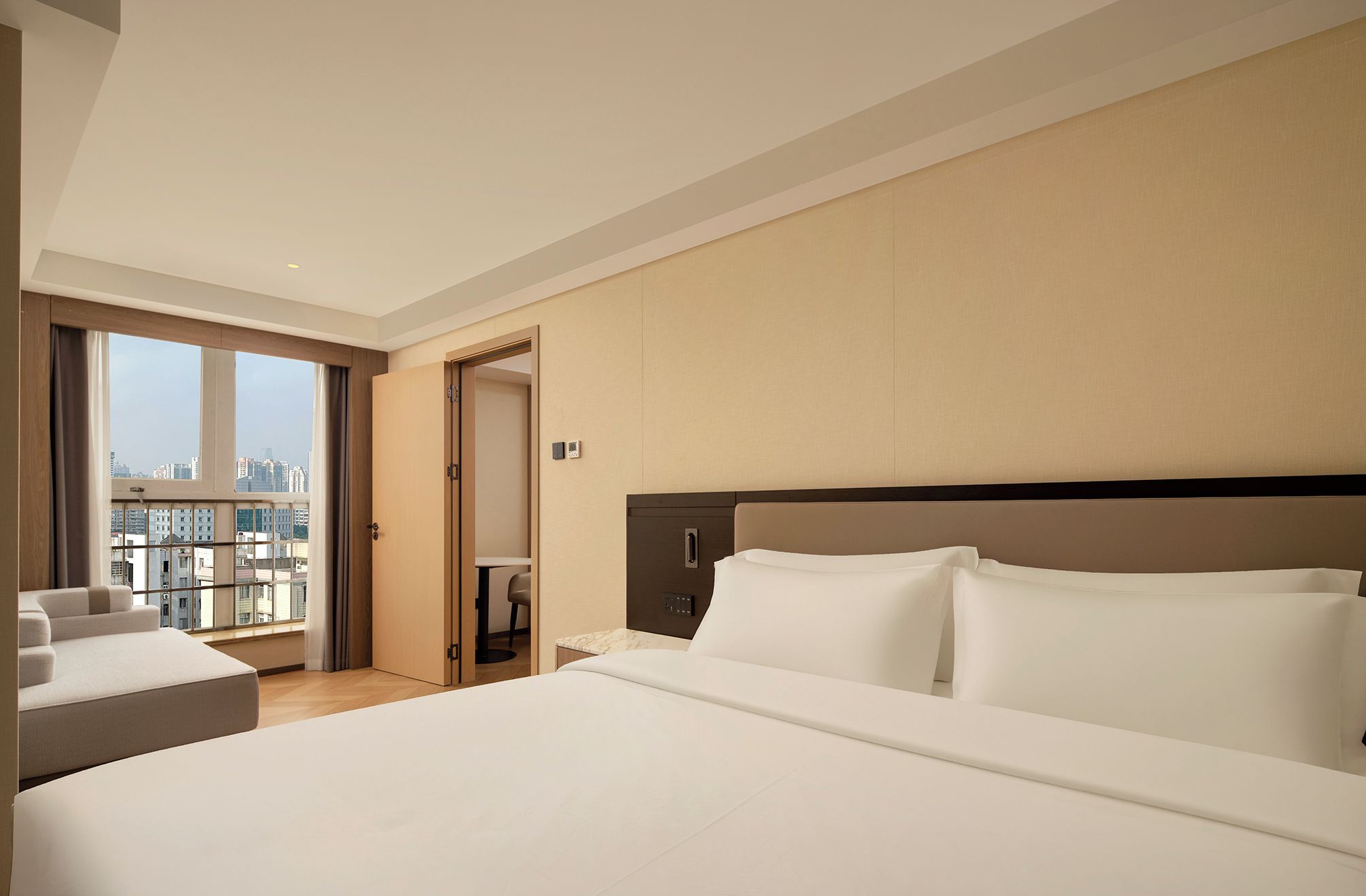 Een hotelkamer met een groot bed, een bureau en uitzicht op de stad.