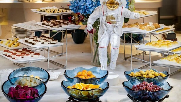 A buffet with various desserts and fruits, including cakes, pastries, and bowls of fruit.