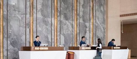 A hotel reception area with marble walls and reception desks.