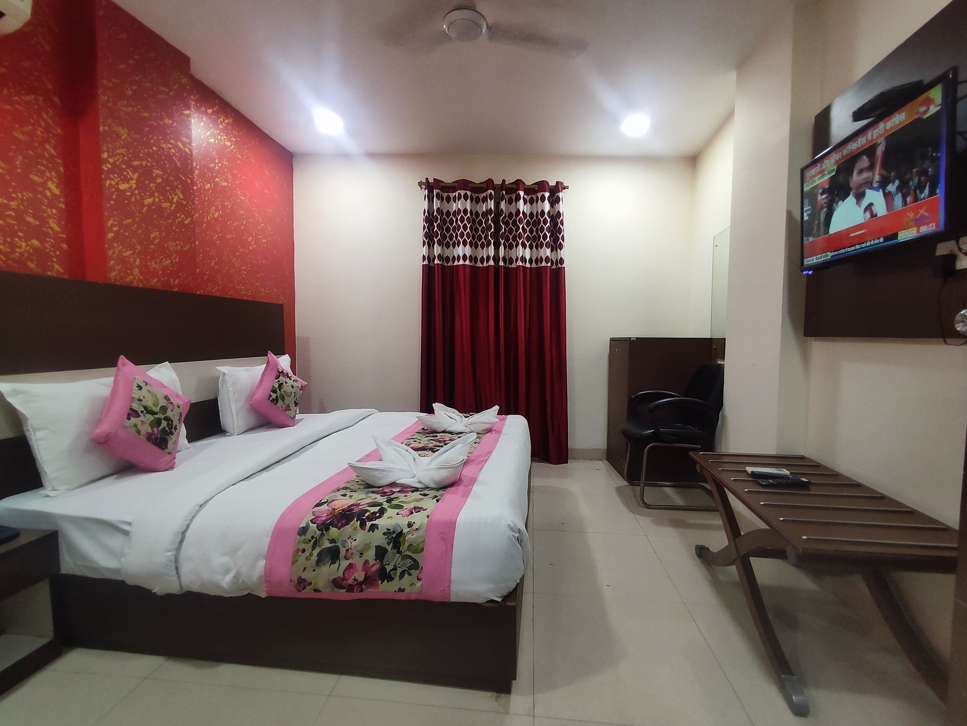 A hotel room with a bed, a desk, a chair, a television, and a curtain.
