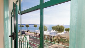 A view from a balcony with a green railing, overlooking a beach with umbrellas and people. - Ocean Dream Apartment (Piran)