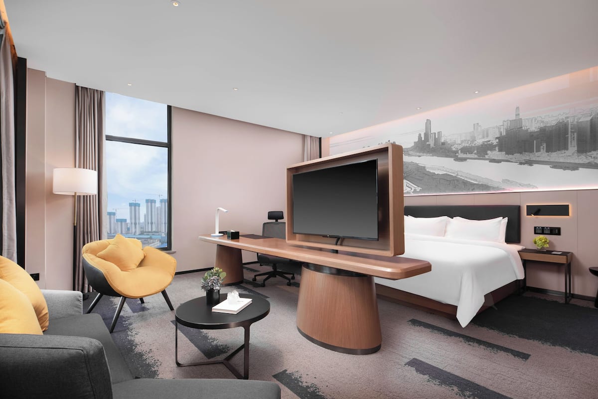 Habitación de hotel moderna con una cama grande, un televisor de pantalla plana, un sofá, un escritorio y vistas a la ciudad.