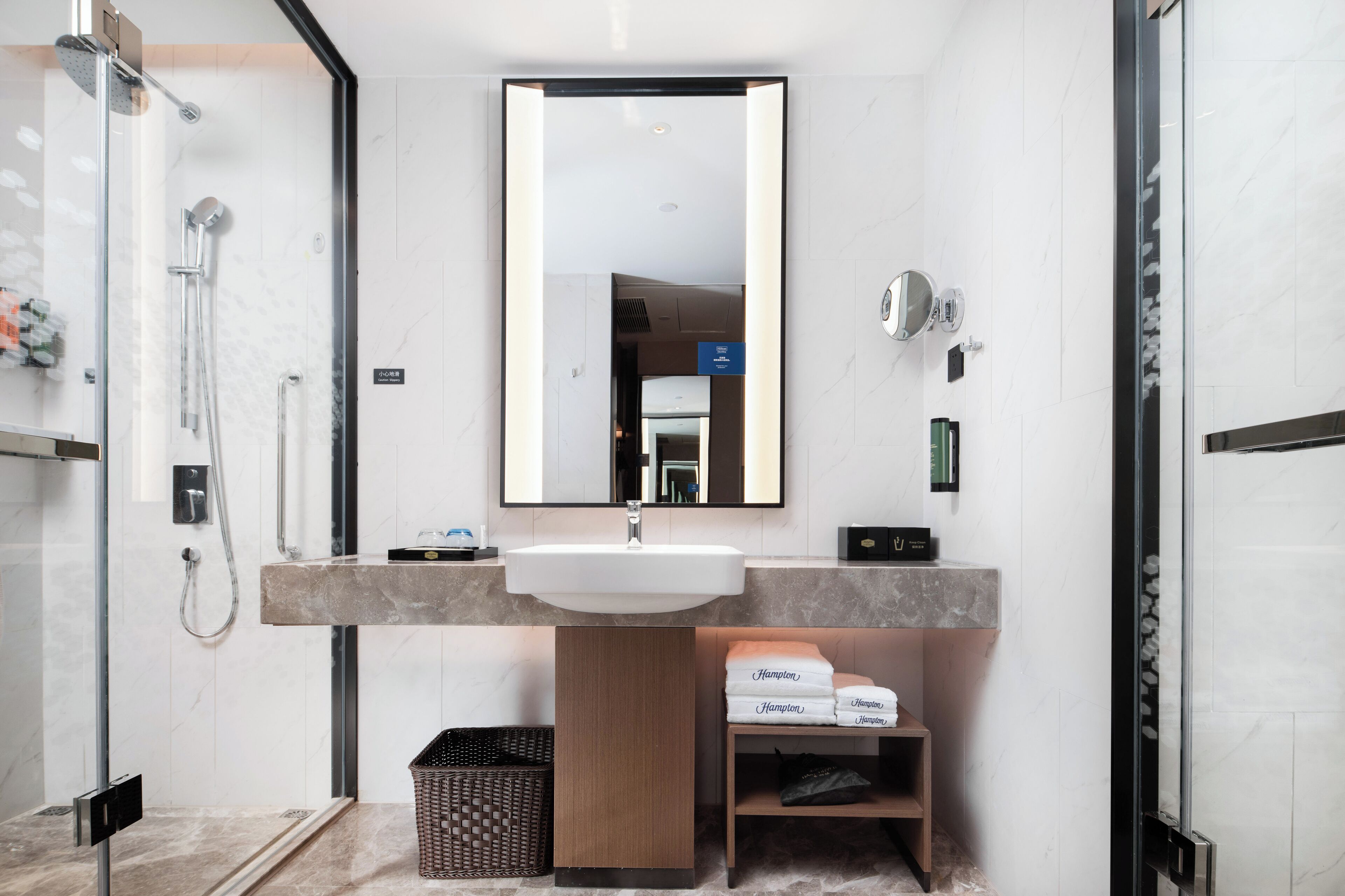 Un baño moderno con un lavamanos amplio, espejo y ducha.