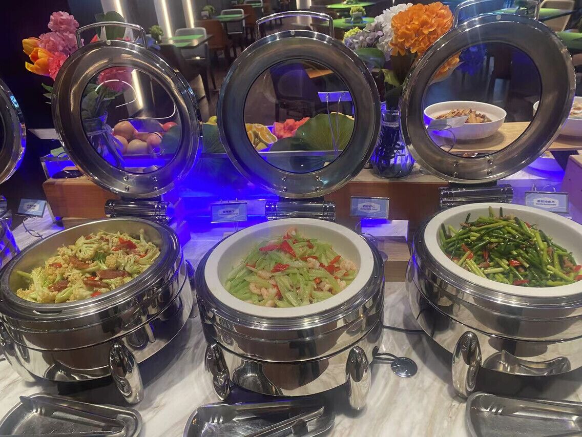 A buffet with various dishes in metal chafing dishes, including salads and stir-fries.