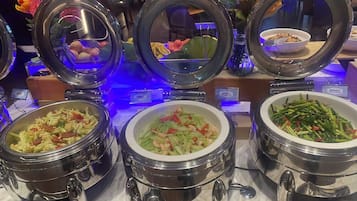 A buffet with various dishes in metal chafing dishes, including salads and stir-fries.