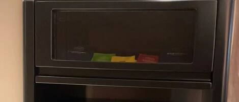 A black minibar with a glass door and a small shelf above it.