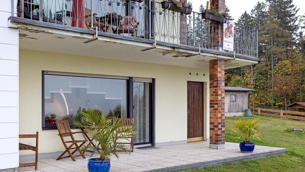 Un immeuble résidentiel doté d’un balcon, de grandes portes-fenêtres coulissantes et de plantes en pot.