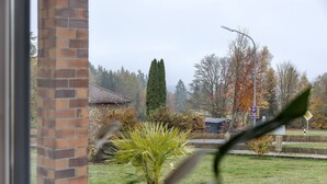 Un quartier résidentiel avec un immeuble en briques, un grand arbre à feuilles persistantes et une rue avec un panneau de signalisation.
