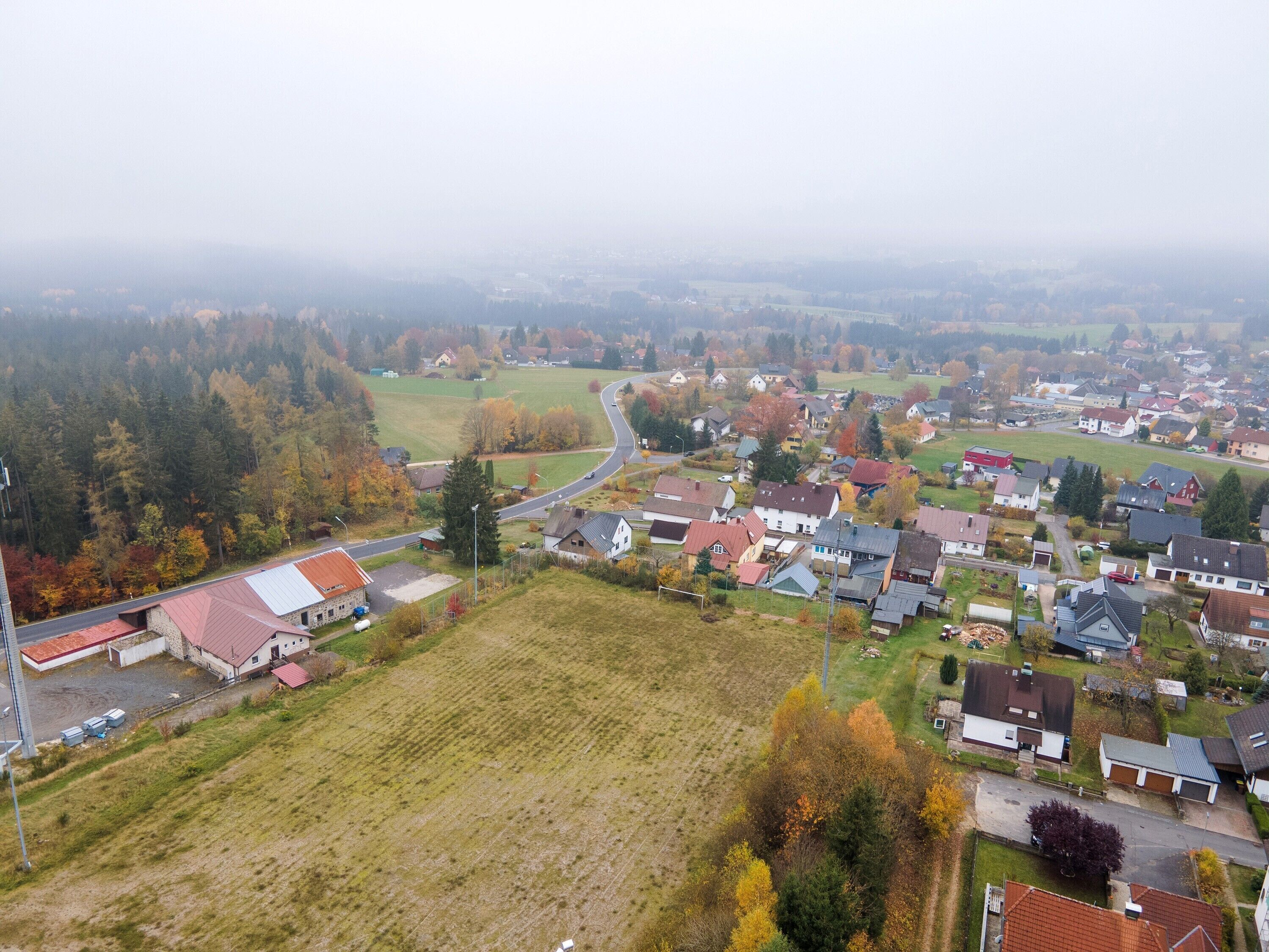 En vy över en lantlig by, tagen från luften, med hus, vägar och åkrar.