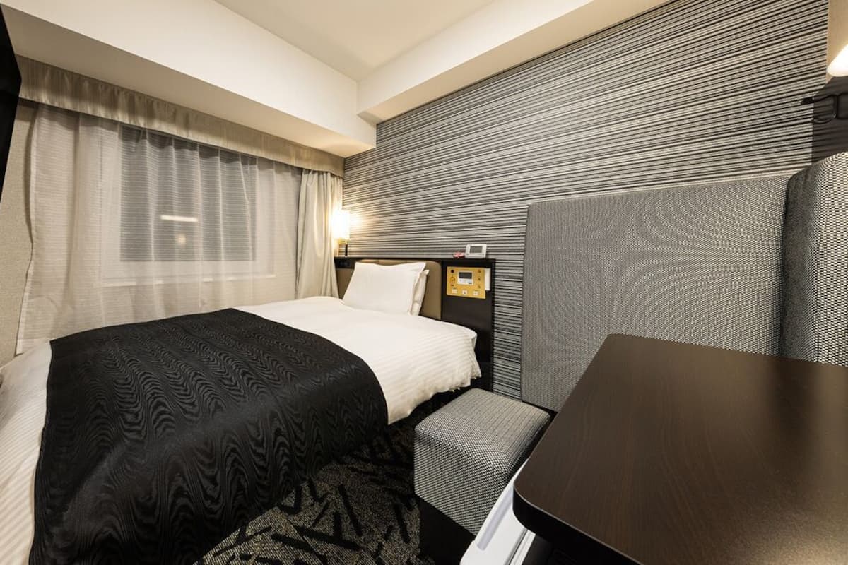 A hotel room with a bed, bedside table, and a television.