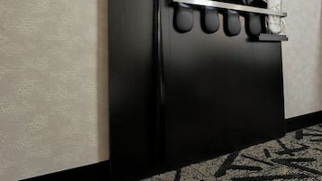 A black wall with a shoe rack holding several pairs of shoes.