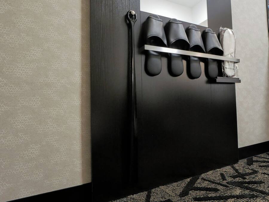 A black wall with a shoe rack holding several pairs of shoes.