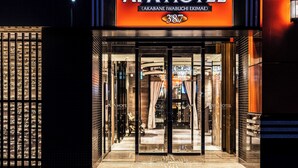The exterior of APA Hotel with a glass entrance and a number 387 sign. - APA Hotel Akabane Iwabuchi Ekimae (Tokyo)
