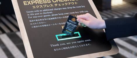 A sign with instructions for guests to drop off their room keys at the checkout area.