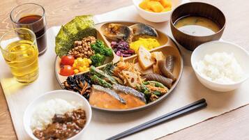 A traditional Japanese meal with various dishes, including rice, vegetables, and fish, served on a wooden table.