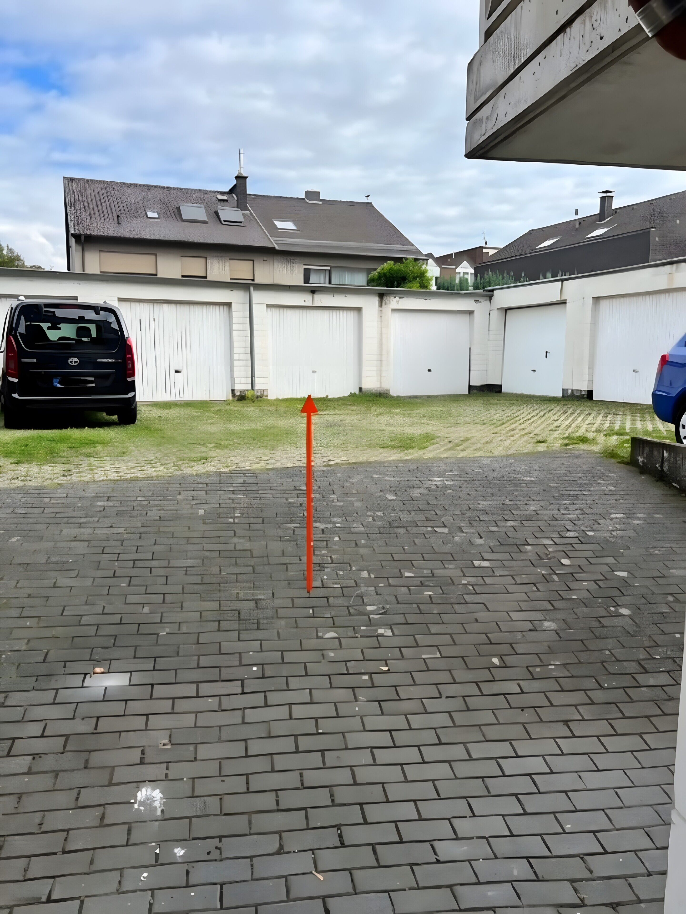 A parking area with a red arrow, a black SUV, and a blue car.