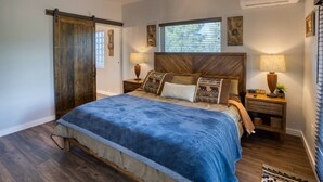 A bedroom with a bed, wooden headboard, two bedside tables with lamps, a ceiling fan, and a window with blinds. - Cabin Retreat in the White Mountains of Arizona (Show Low)