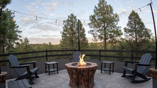 An outdoor seating area with a fire pit, chairs, tables, and a wooden fence. - Cabin Retreat in the White Mountains of Arizona (Show Low)