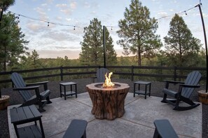 An outdoor seating area with a fire pit, chairs, tables, and a wooden fence. - Cabin Retreat in the White Mountains of Arizona (Show Low)