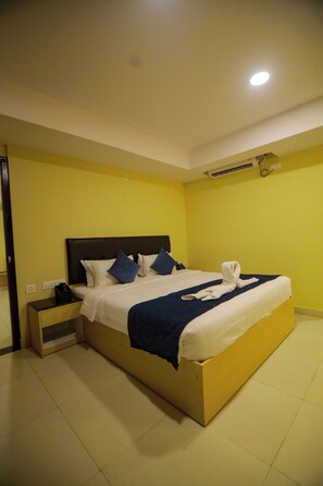 Una habitación de hotel con una cama grande, una mesita de noche y un aire acondicionado instalado en la pared.