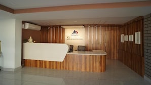 A reception desk with a wooden finish, a logo, and a sign indicating a resort and convention center. - MJ Avyanna Resort & Convention Centre (Anekal)
