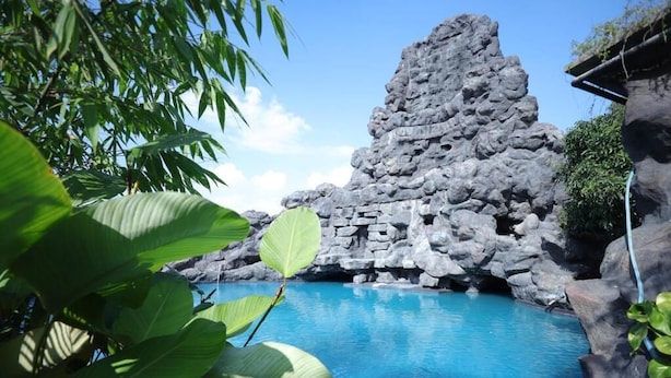 A pool with clear blue water, surrounded by rocky formations and lush green foliage. - MJ Avyanna Resort & Convention Centre (Anekal)
