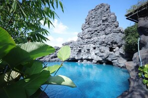 Una piscina con agua azul cristalina, rodeada de formaciones rocosas y exuberante follaje verde.
