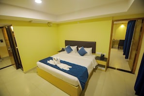 Habitación de hotel con cama, mesitas de noche, espejo y baño visible a través de una puerta abierta.