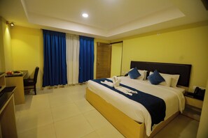 A hotel room with a large bed, a desk, and a chair. - MJ Avyanna Resort & Convention Centre (Anekal)