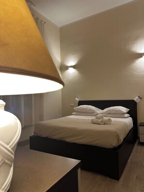 A neatly made bed with pillows and a rolled towel, a bedside table, and a lamp. - Double room with private bathroom in Terralba  (Oristano) - Helichrysum (Terralba)