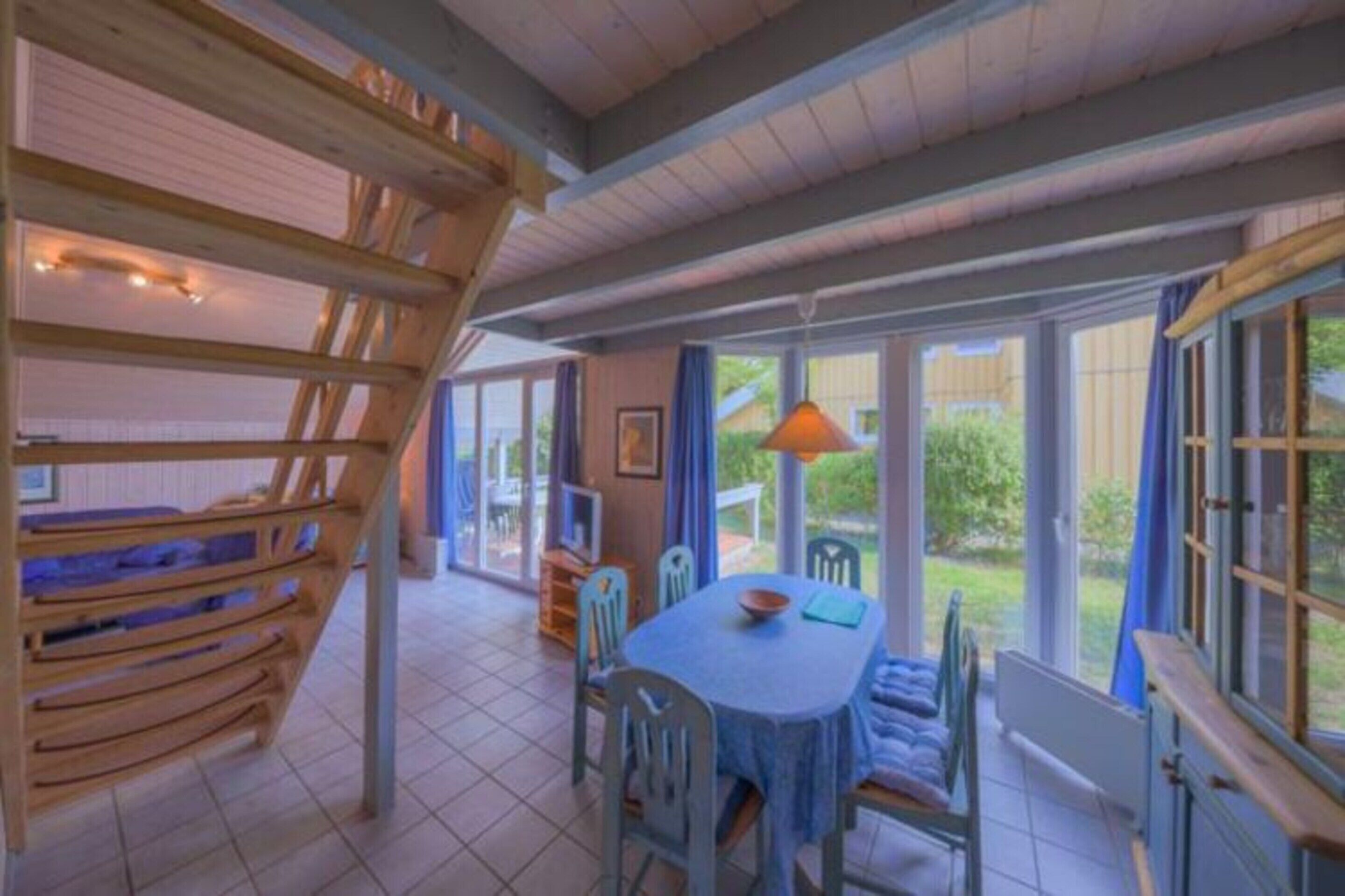Un espace repas comprenant une table et des chaises, un banc en bois et de grandes fenêtres.