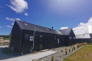 A modern building with a metal roof and a gravel pathway leading to the entrance. - Sky Valley (Lake Tekapo)