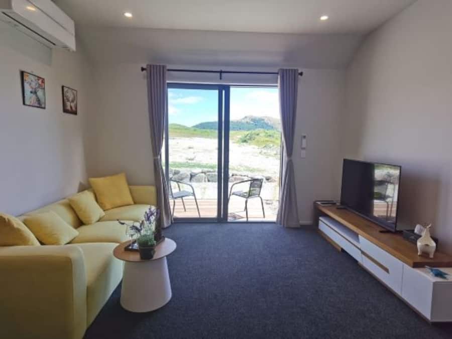 Una sala de estar moderna con sofá, televisor y vistas a través de un ventanal.