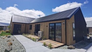 A modern house with a sloped roof, large glass windows, and a wooden exterior. - Sky Valley (Lake Tekapo)