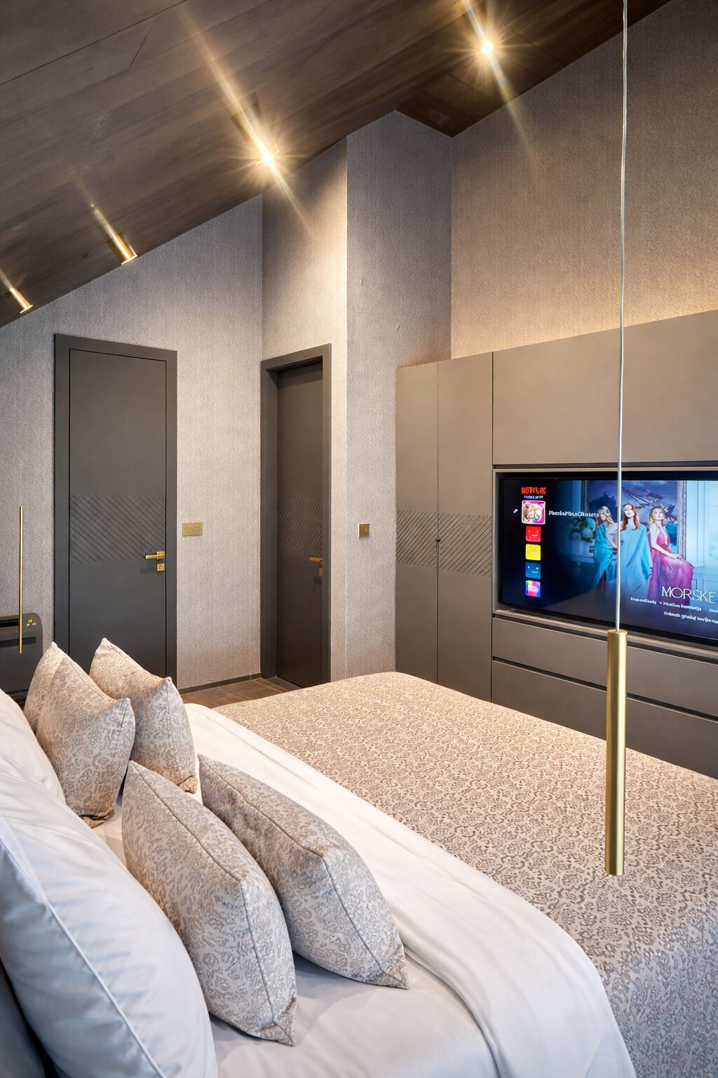 A modern bedroom with a large bed, a TV mounted on the wall, and a door with a keypad lock.
