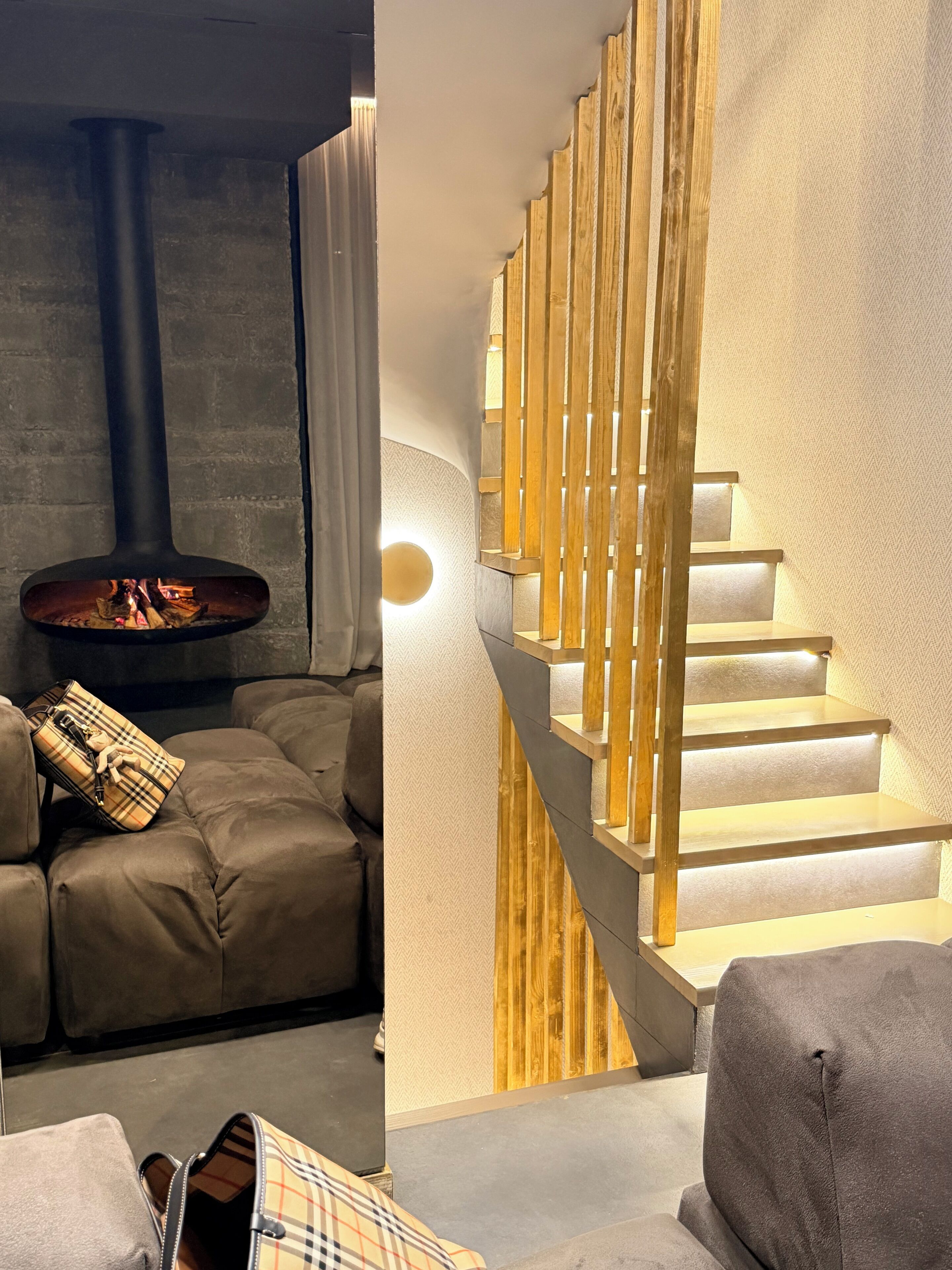 Una sala de estar moderna con chimenea, un sofá y una escalera con barandillas de madera.