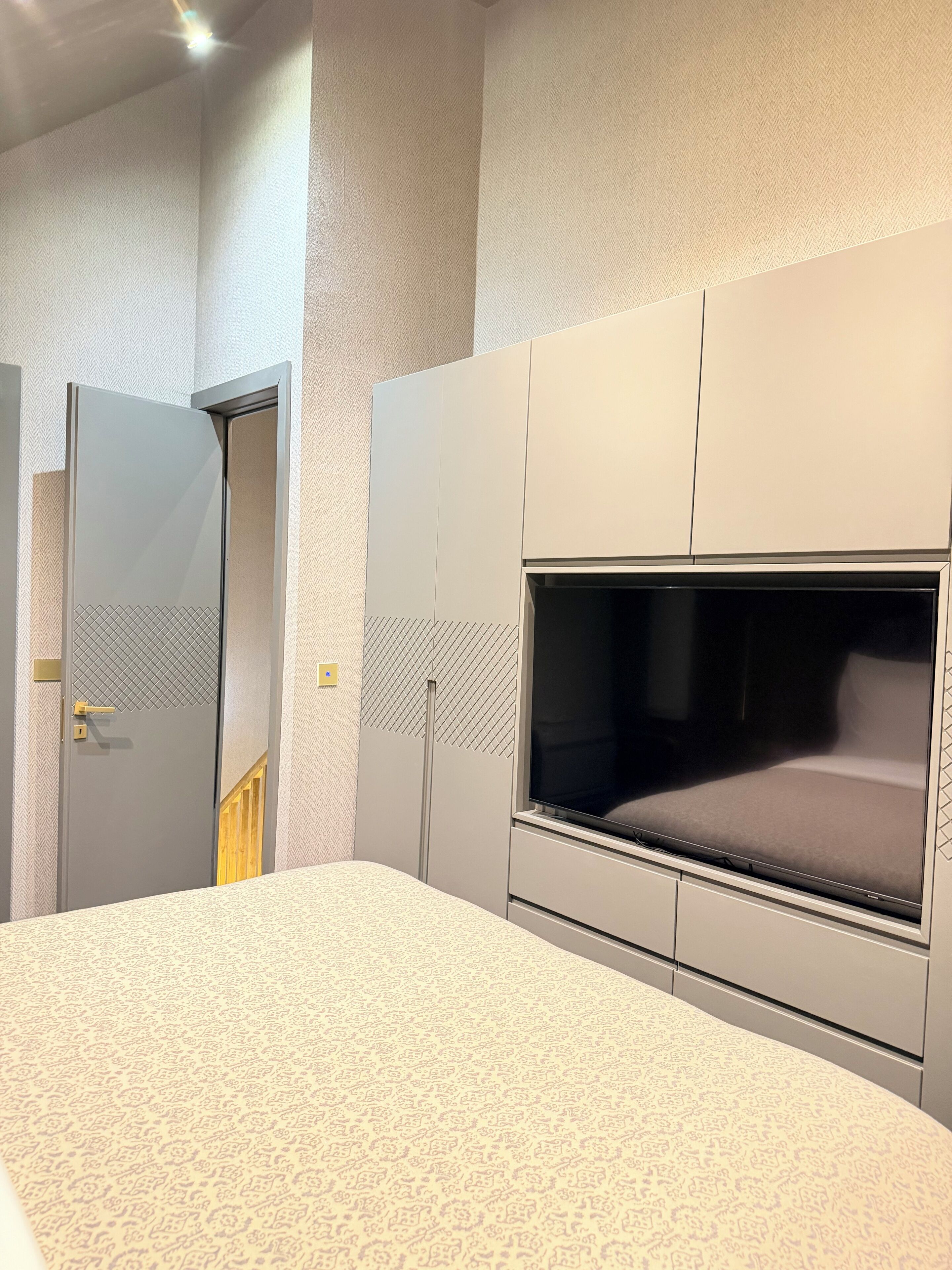 A bedroom with a bed, a TV, and a wardrobe.