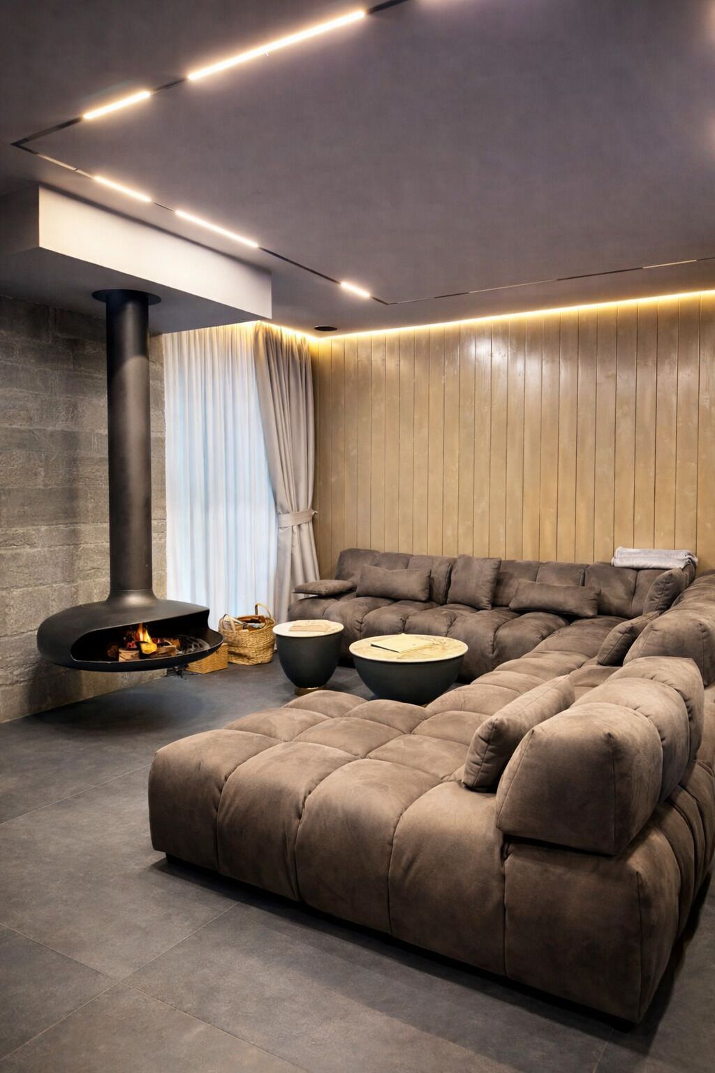 A modern living room with a sectional sofa, a fireplace, and contemporary lighting.