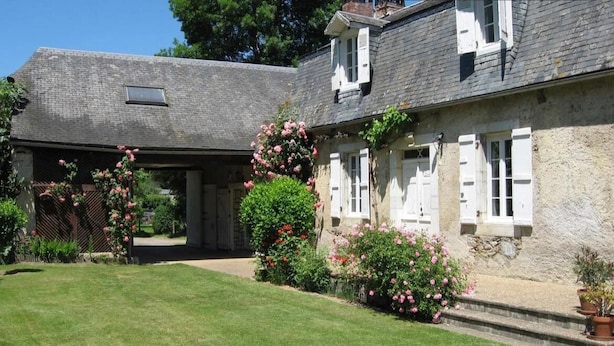 A stone house with white shutters, a covered porch, and a well-maintained lawn. - La Caminade (Bourg-de-Bigorre)