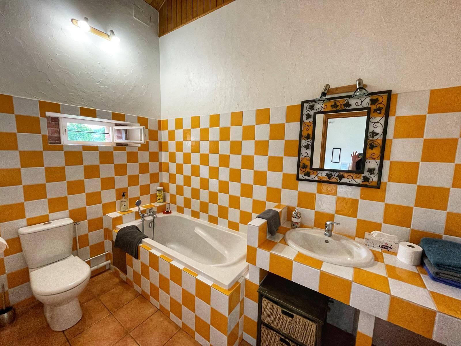 Un bany amb un dibuix de rajoles de quadres, un vàter, una banyera i un lavabo.