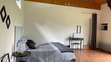 Un dormitorio con cama, una mesita, una silla y un escritorio.