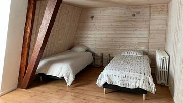 Una camera da letto mansardata piccola e accogliente con due letti, travi in legno e termosifone.