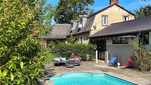 A swimming pool with lounge chairs, a house with a sloped roof, and a clear blue sky. - La Caminade (Bourg-de-Bigorre)