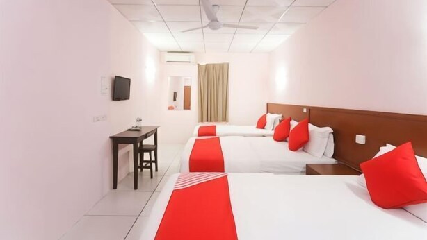 Une chambre d’hôtel avec deux lits, un bureau, une télévision et un ventilateur de plafond.