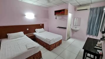 A hotel room with two beds, a desk, a sink, and a mirror.