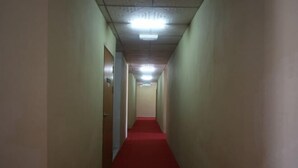 Un couloir étroit, avec un tapis rouge, des murs de couleur beige et des portes de part et d’autre.