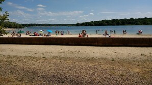 Une plage avec des gens, des bateaux et un ciel dégagé.