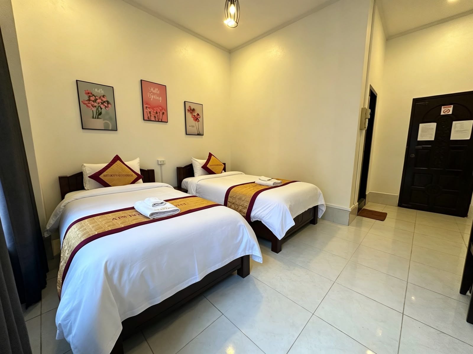 Habitació d'hotel amb dos llits, una porta i una paret amb tres quadres.