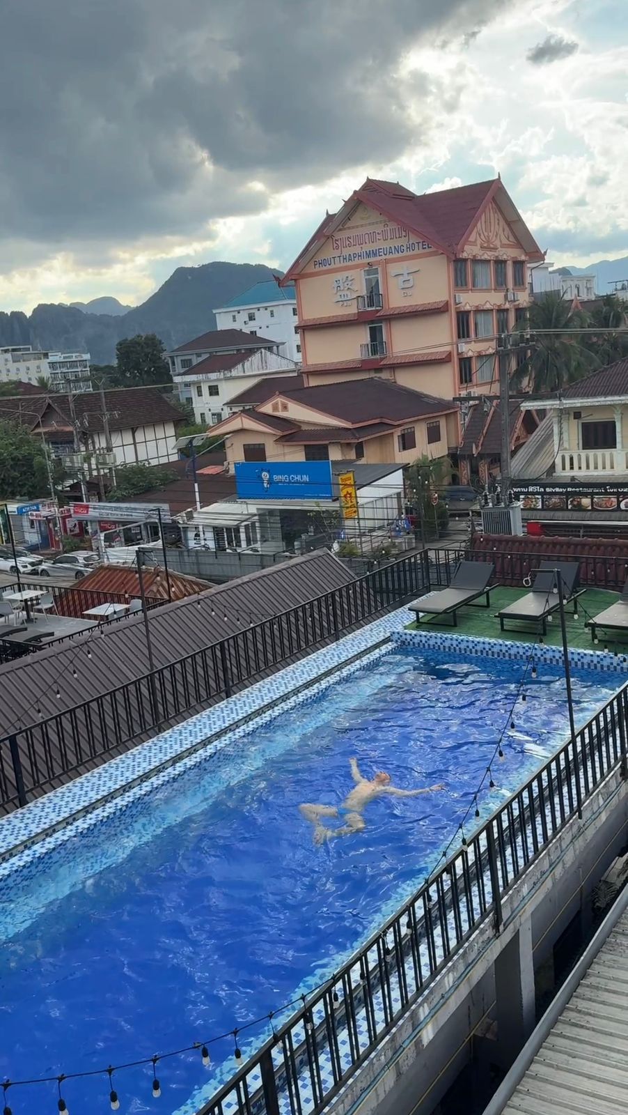 A swimming pool with a tiled deck and a person swimming.