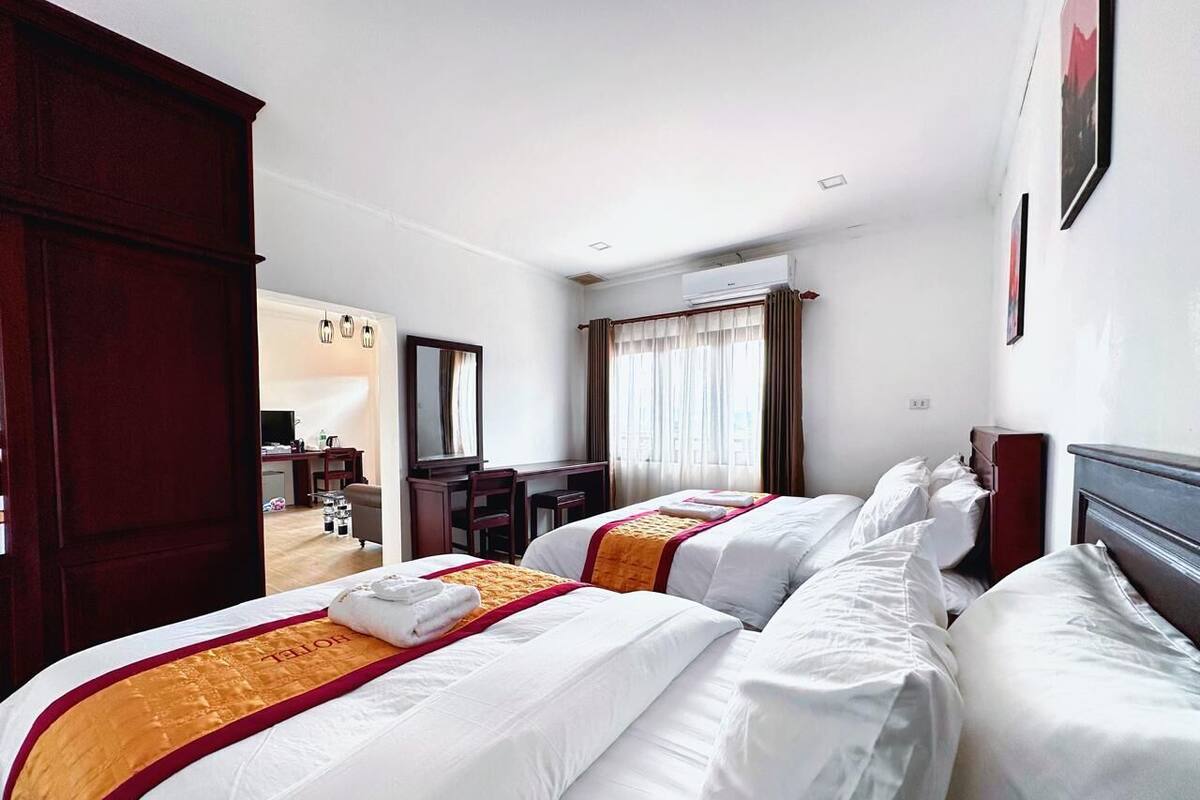 Een hotelkamer met twee bedden, een bureau, een stoel en een kledingkast.